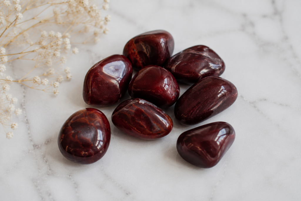 Piedras para el amor: rodados de granate natural en primer plano sobre fondo blanco